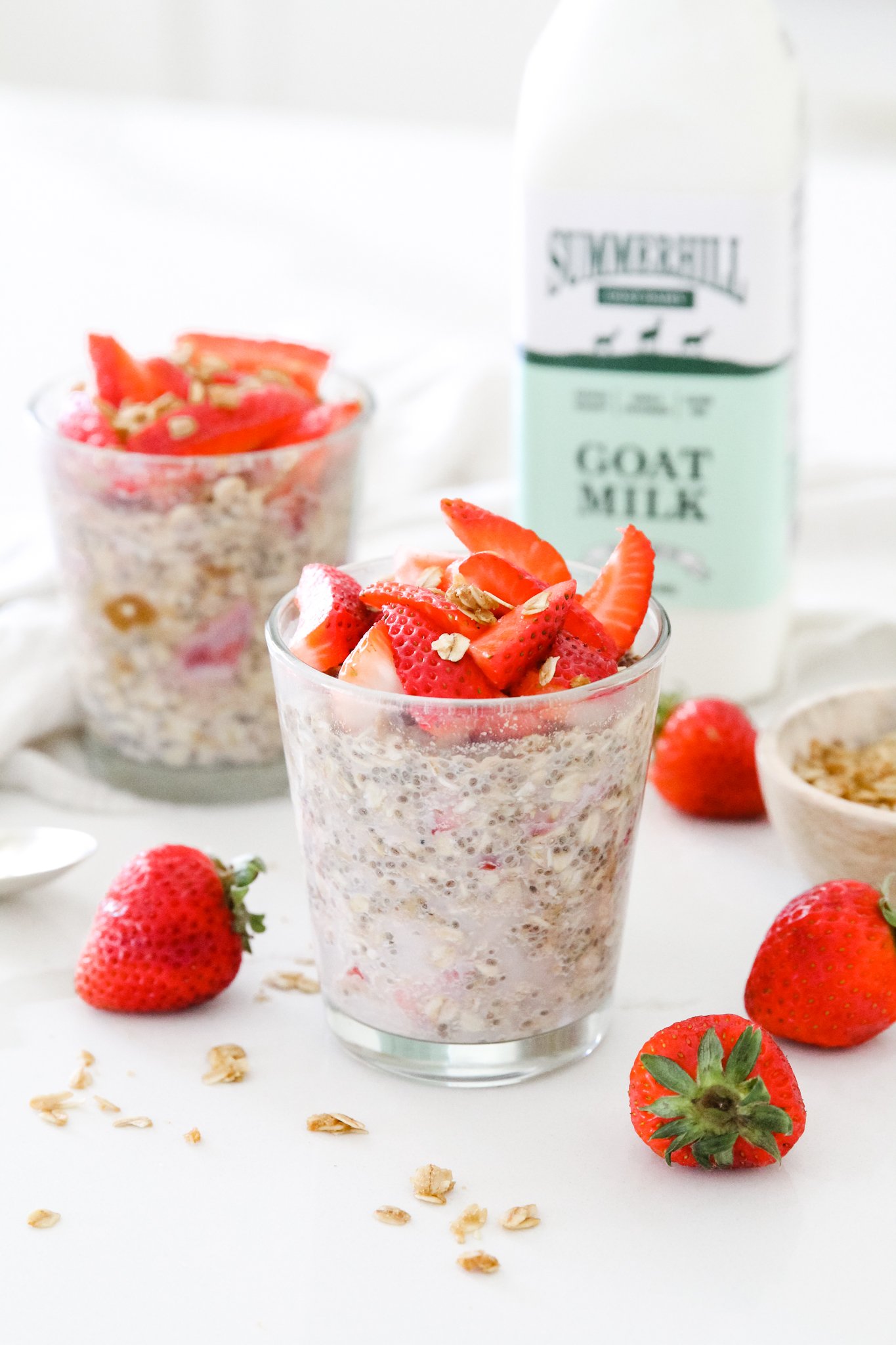 overnight oats in a jar topped with strawberries, with a bottle of Summerhill goat milk in the background.