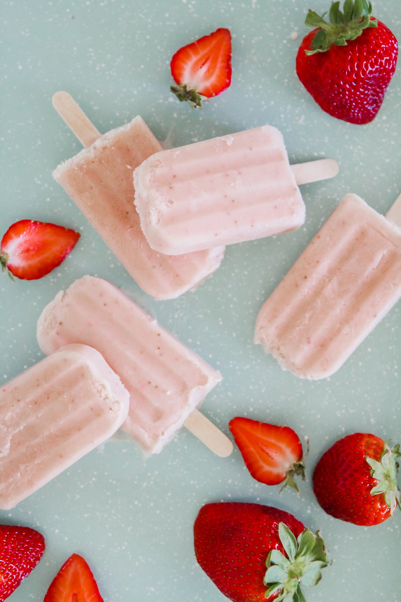overhead view of pink banana cream popsicles, with strawberries for decoration