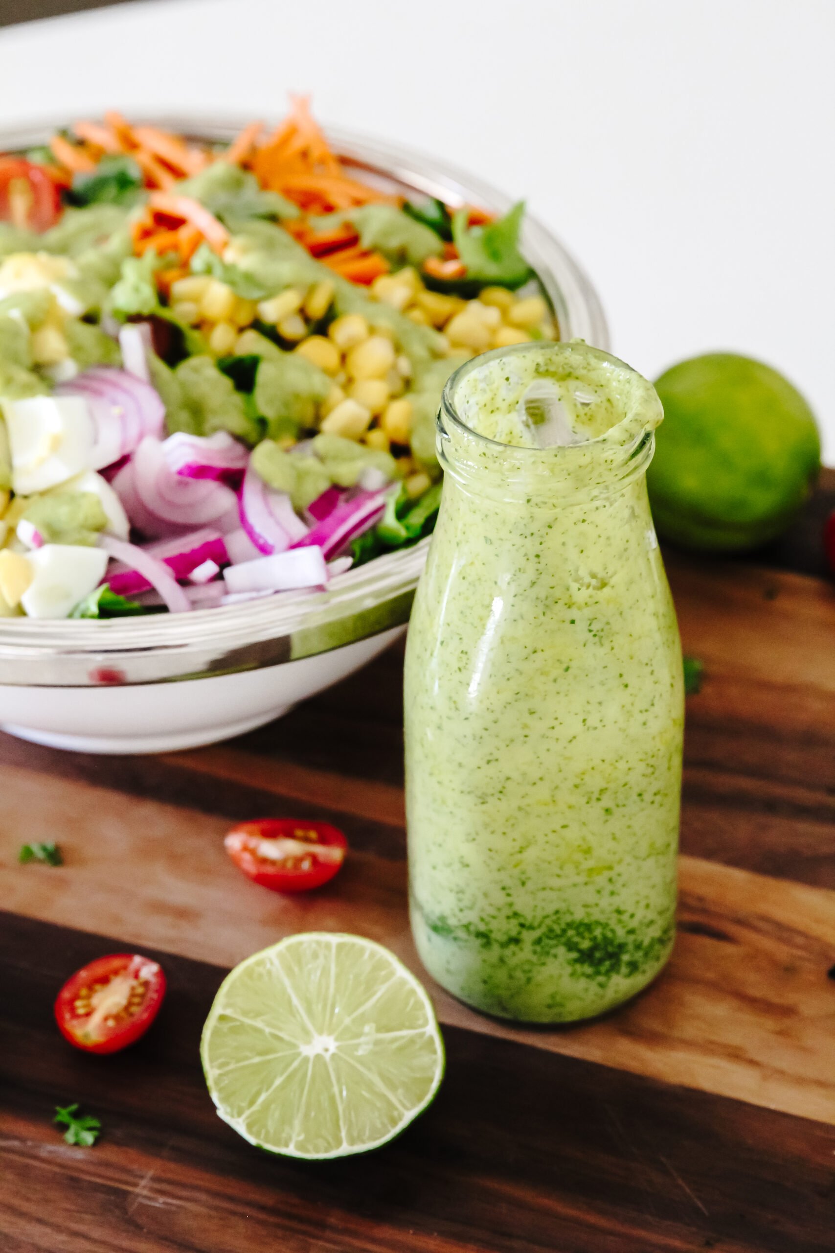 glass milk filled with green dressing in foreground, salad in background